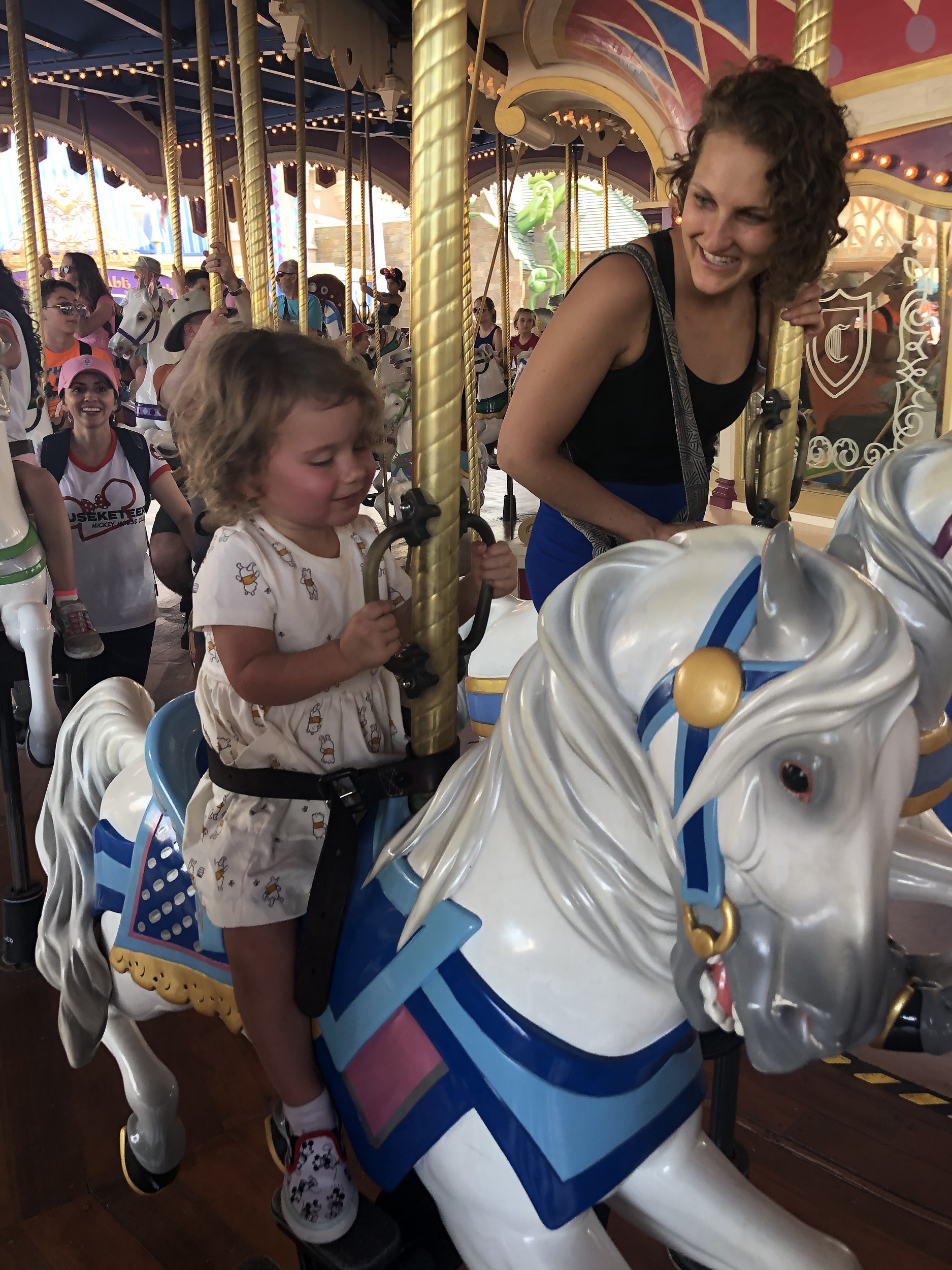 A toddler rides the carousel in Disney World.
