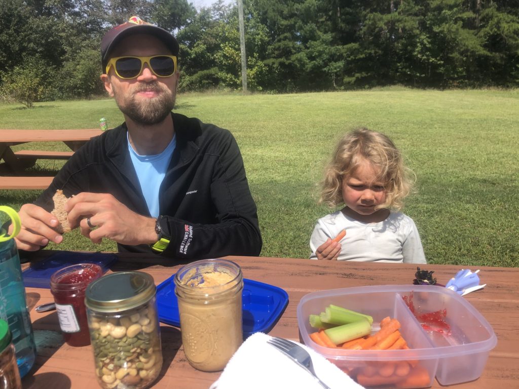 Father and Toddler eating lunch outside on a road trip