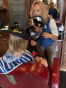 Toddler gets their first haircut at Harmony Barber Shop in Magic Kingdom
